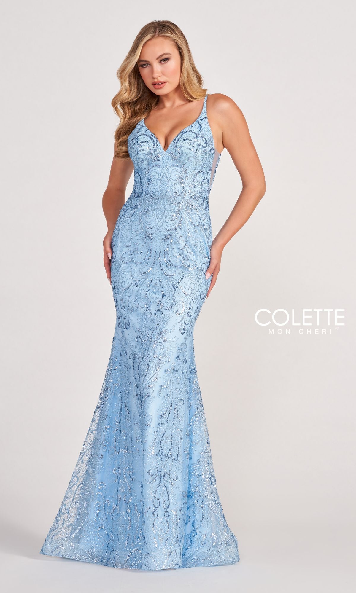 A woman poses against a plain background in the Colette CL2019 Long Prom Dress in Glitter-Sequin, a light blue, floor-length gown with thin straps, a V-neckline, fitted silhouette, and sparkling sequin detailing.